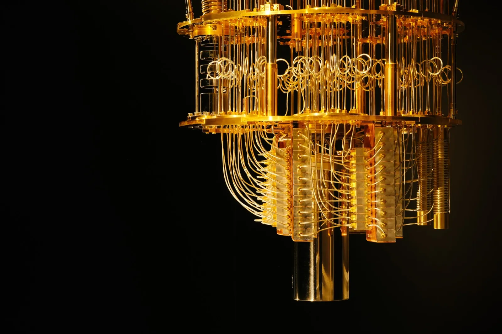The tiered gold wiring and dilution refrigerator of a quantum computer against a black background